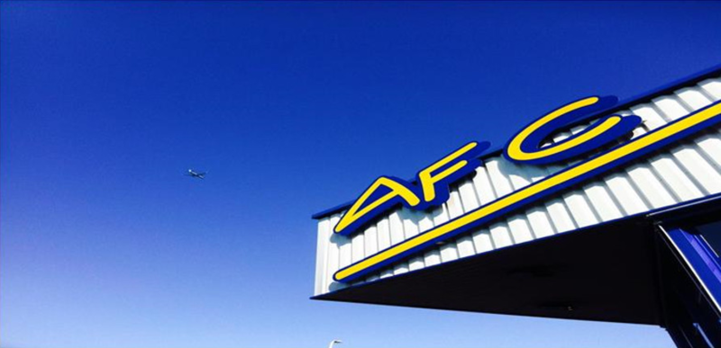 Enseigne AFC sur façade d'atelier sous un ciel bleu